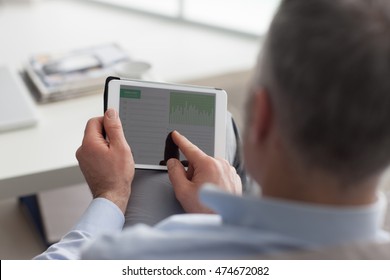 Man sitting on the couch and using a digital touch screen tablet, he is tapping with his finger