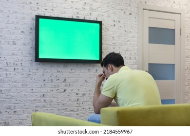 Man Sitting On The Couch And Watching Tv. Green Screen Concept	