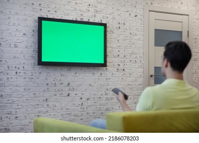 Man Sitting On The Couch And Watching Tv. Green Screen Concept	