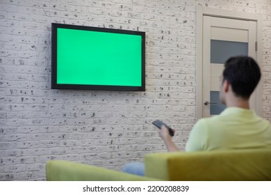 Man Sitting On The Couch And Watching Tv. Green Screen Concept	