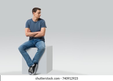 Man sitting on a cube and looking away - isolated. Space for text