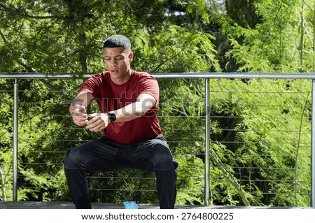 Man sitting on deck after fitness set, resting animated heartrate rising above wrist and water icon. Male, outdoor, workout, athletic, focus, greenery, balcony
