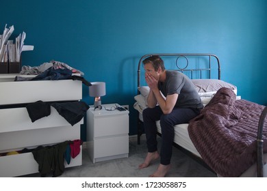 Man Sitting On Edge Of Bed Looking Anxious