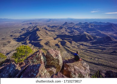 Man Sitting On Edge Of Cliff Overlooking Desert Landscape - Chisos Mountains South Rim, Big Bend National Park, Texas