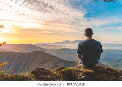 Man sitting on a edge of a cliff and looking at beautiful and rough terrain around him. Adventure solo traveling lifestyle. Wanderlust adventure concept. Active weekend vacations wild nature outdoor.  - Powered by Shutterstock