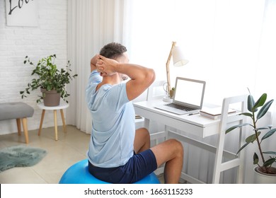 Man Sitting On Fitness Ball While Working At Home