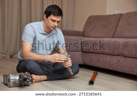 Man sitting on floor assembling parts of a vacuum cleaner