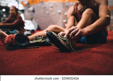 Man sitting on the floor and wearing griping shoes for wall climbing. Cropped shot of man tying shoe laces at a wall climbing gym. - Powered by Shutterstock