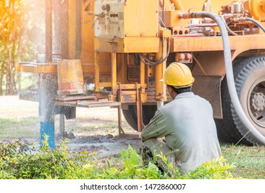 the man sitting on ground waiting for A Ground water hole drilling machine by  the old truck outside Bangkok.