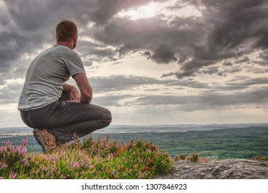 Man Sitting On Hill Summit. Conceptual Scene. He Was Wearing Light Outdoor Clothes. He Was Looking Forward With Determination