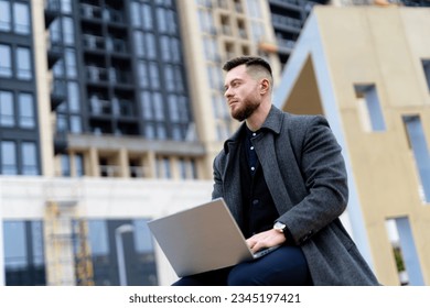 A man sitting on a ledge using a laptop