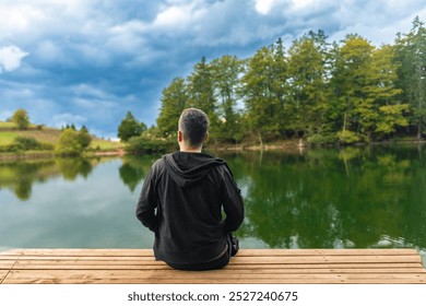 A man sitting on the porch and watching the lake - Powered by Shutterstock