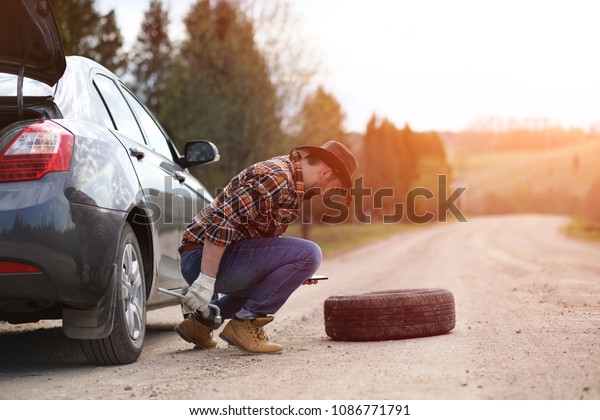 The\
man is sitting on the road by the car in the\
nature\

