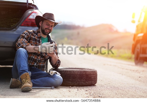 The\
man is sitting on the road by the car in the\
nature\
