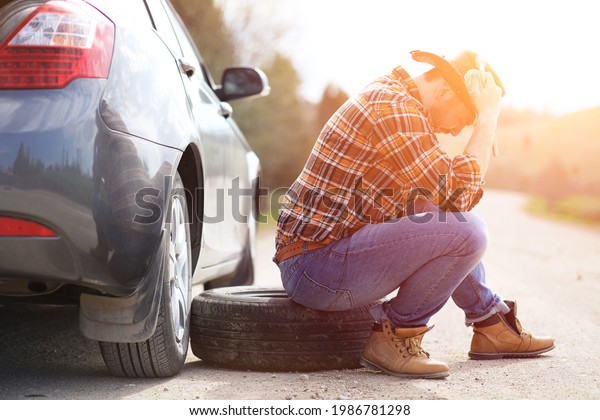 The
man is sitting on the road by the car in the
nature
