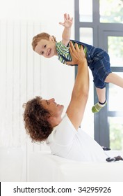 man sitting on sofa and lifting up his son