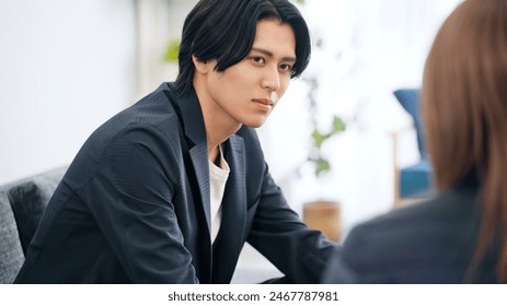 A man sitting on a sofa and talking to a woman. - Powered by Shutterstock