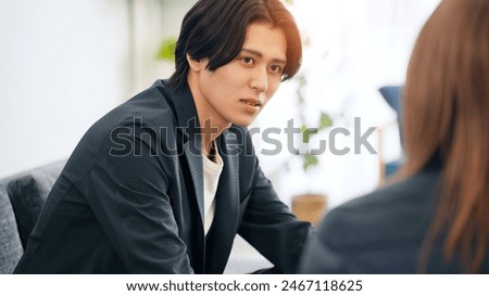 A man sitting on a sofa and talking to a woman.