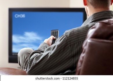 Man Sitting On A Sofa Watching Tv Holding Remote Control