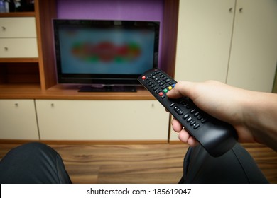 Man Sitting On A Sofa Watching Tv Holding Remote Control