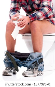 Man Is Sitting On The Toilet Bowl, Holding Paper In Hands