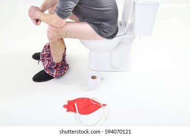 Man Sitting On A Toilet With Enema Bag 