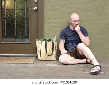 A Man Sitting Outside His House In Dissapointment