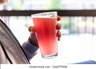 Man Sitting Outside Holding Drinking Glass Of Red Pink Lemonade Cocktail Juice Closeup Of Drink Color