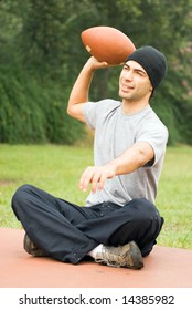 A Man Sitting, Preparing To Throwing A Football, At A Park, Smiling. - Vertically Framed