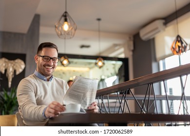 Man sitting at a restaurant table, reading newspaper and drinking coffee - Powered by Shutterstock