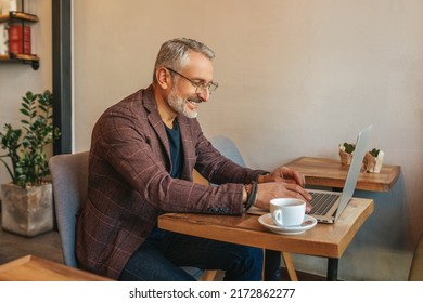 Man sitting sideways to camera working on laptop