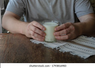 Man Sitting At The Table With Glass Of Kefir In His Hands. The Use Of Kefir For Food. Adult Male, Caucasian. Age 44-45. Lifestyle.