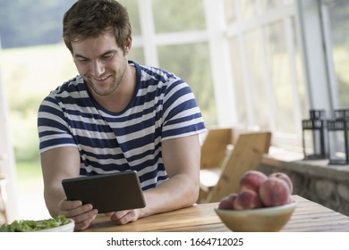 A man sitting at a table using a digital tablet.
