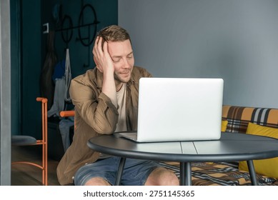 Man sitting at table using laptop computer at home and smiling during online communication. Online conversation, video call with family or friends. Digital communication and connection from home
