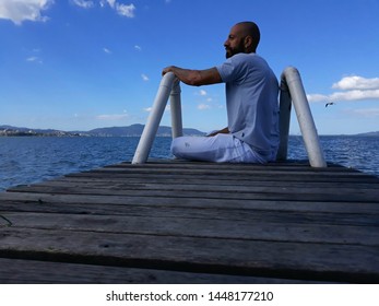 Man sitting at the warehouse looking to the side.  Man sitting by the sea.  Man sitting on the blue sky sea. - Powered by Shutterstock