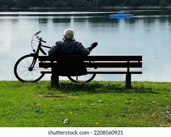 Man is sitting and watching on the lake putting his legs on the bicycle - Shutterstock ID 2208560921