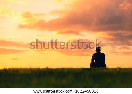 Man sitting watching sunset. Enjoying a peaceful moment, thinking, getting away from it all concept. 