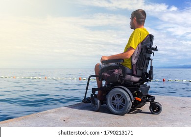 Man sitting in a wheelchair on the beach. Dangers of jumping into water from heights. Head and spine injury.