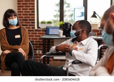 Man sitting in wheelchair, talking at group therapy session with people having alcohol addiction. Patients with face masks attending aa meeting to have discussion with psychologist. - Powered by Shutterstock