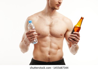 Man With A Six Pack Holds Beer Bottle In One Hand And Water Bottle In The Other.