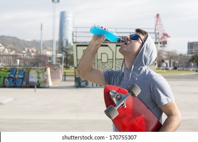 Man With Skateboard Drinking Energy Drink After Sport.