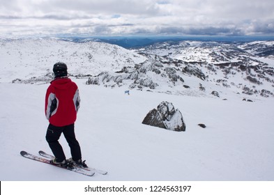 A Man Skier In A Red Jacket Standing On Top Of The Ski Slope And Looking Towards The Snow Covered Hills In Perisher Ski Resort, New South Wales, Australia