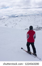 A Man Skier In A Red Jacket Standing On Top Of The Ski Slope And Looking Towards The Snow Covered Hills In Perisher Ski Resort, New South Wales, Australia