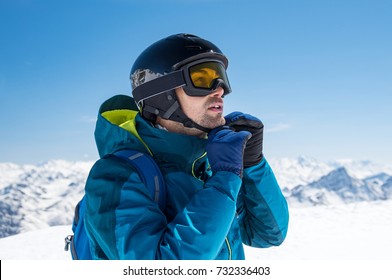 Man Skier Wearing Helmet And Ski Mask On Snowy Mountain. Man Getting Ready For A Ski Trip In Winter. Young Skier Looking At Mountain Covered By Snow.