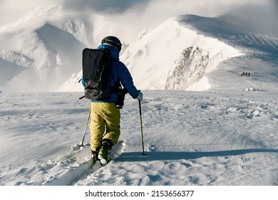 Man skier wiith ski equipment making his way through the untouched snow on winter snowy mountain range.