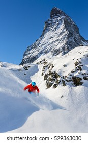 Man Skiing On Fresh Powder Snow With Matterhorn In Background, Zermatt In Swiss Alps.