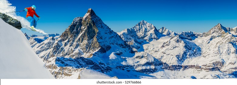 Man Skiing On Fresh Powder Snow With Matterhorn In Background, Zermatt In Swiss Alps.