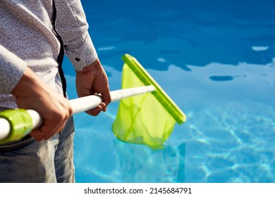 Man With Skimmer Net Equipment Cleaning Swimming Pool From Rubbish. Service And Maintenance Of The Pool. Male Removes Garbage From The Water With A Sap. Swimming Pool Cleaning Service. Hotel Cleaner.