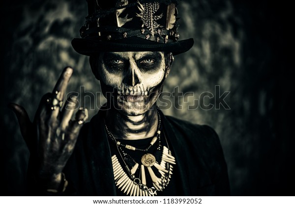 A man with a skull makeup dressed in a\
tail-coat and a top-hat. Baron Saturday. Baron Samedi. Dia de los\
muertos. Day of The Dead.\
Halloween.