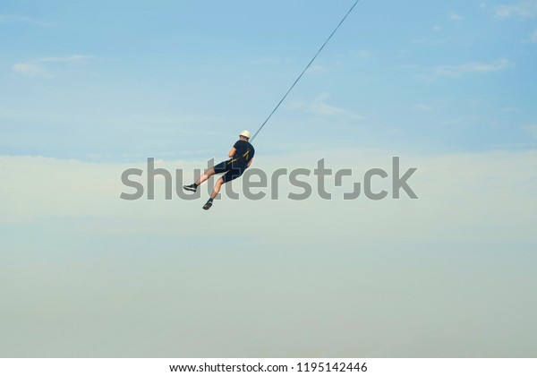 man in the sky\
jumping down on a rope from a bridge in a protective helmet, the\
theme of extreme sports\
